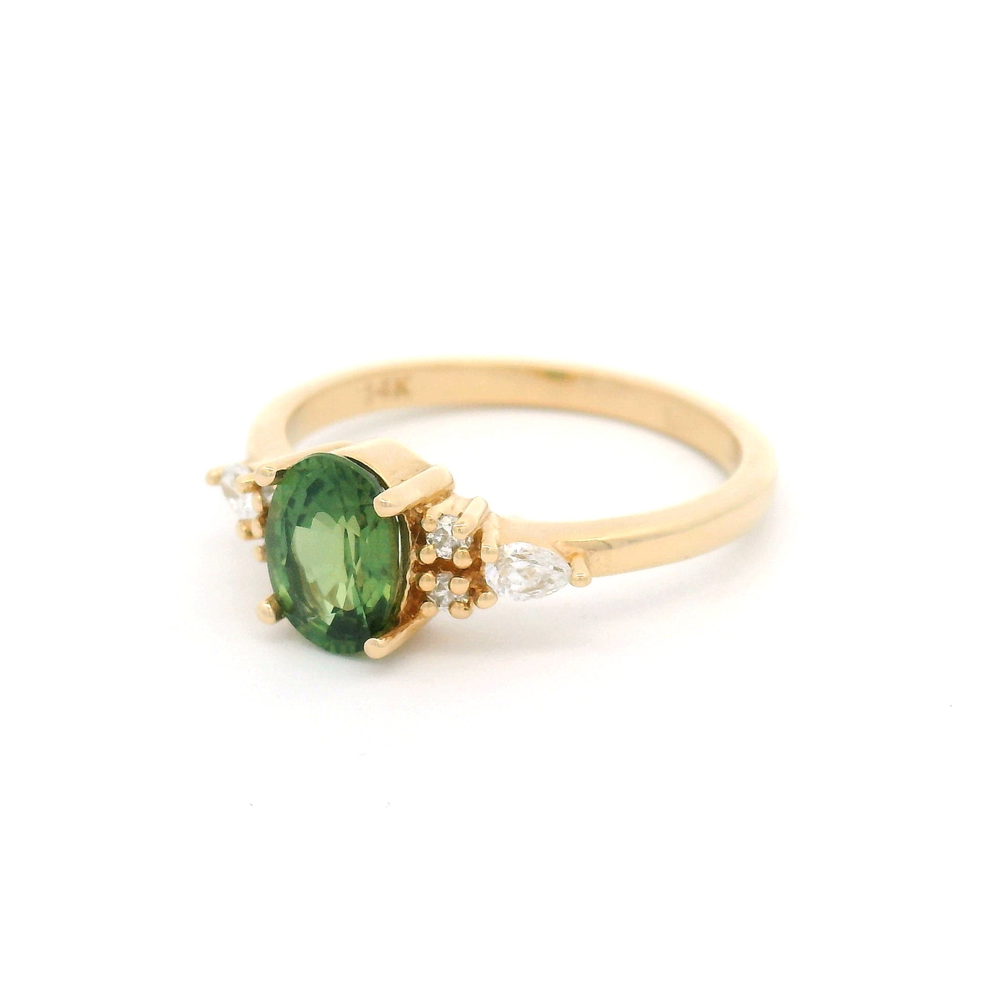 14K yellow gold engagement ring featuring a claw-set natural 1.09ct oval mixed-cut green sapphire with pear-shaped and round brilliant-cut lab-grown diamond accents on a delicate 1.8mm band.