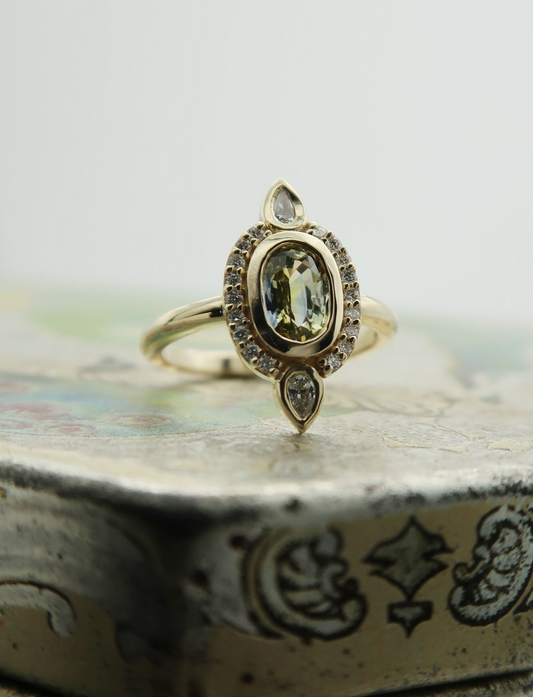 14k yellow gold ring with a low, comfortable profile set with Oval Parti Sapphire and lab grown diamonds in the halo. 