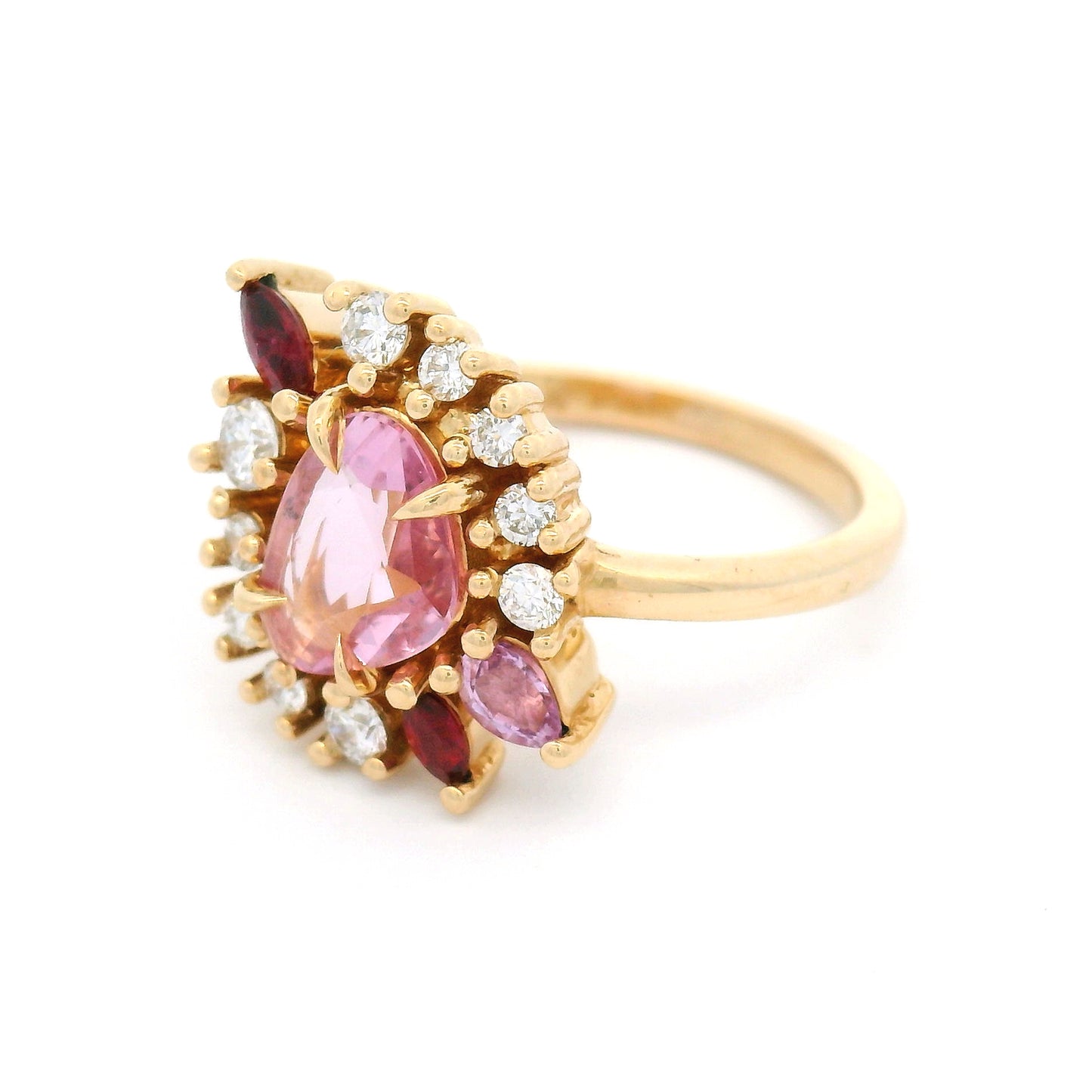 14K yellow gold asymmetrical engagement ring featuring a natural 0.70ct triangular pink sapphire with a halo of mixed-cut pink sapphires, rubies, and lab-grown diamonds totalling 0.23cts.