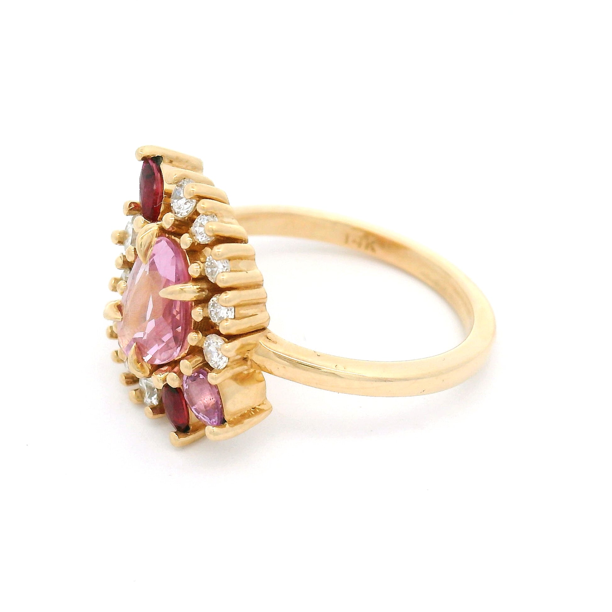 14K yellow gold asymmetrical engagement ring featuring a natural 0.70ct triangular pink sapphire with a halo of mixed-cut pink sapphires, rubies, and lab-grown diamonds totalling 0.23cts.