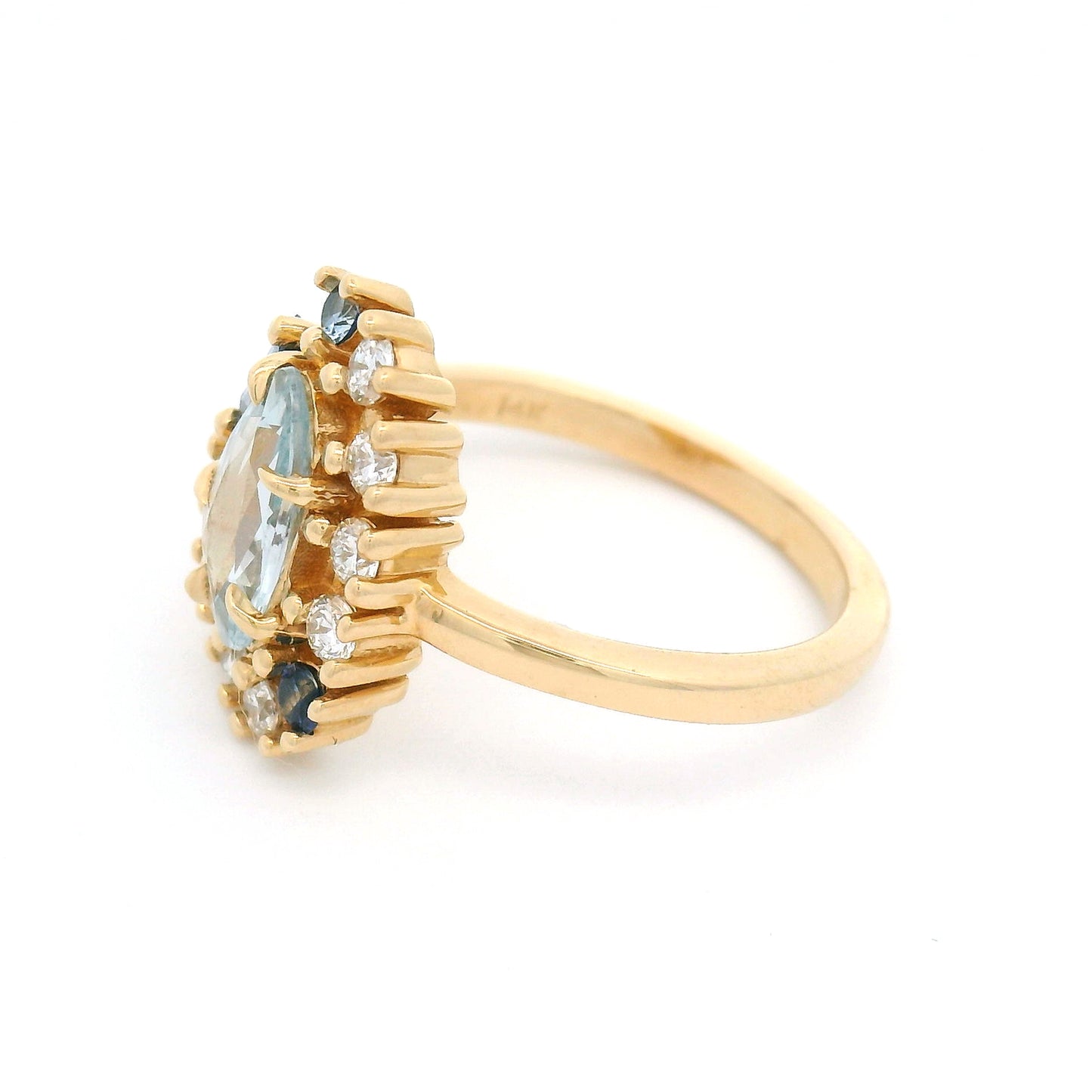 14K yellow gold asymmetrical engagement ring featuring a natural 0.65ct triangular greyish-blue sapphire with a halo of mixed-cut blue sapphires and lab-grown diamonds totalling 0.26cts.