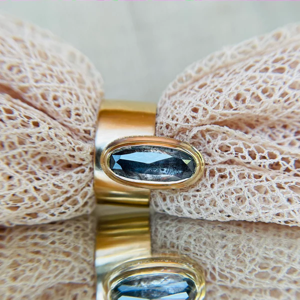 14k yellow gold ring set with a 3.18ct salt and pepper elongated oval rose cut diamond and hidden pave diamonds.  Displayed with fabric.