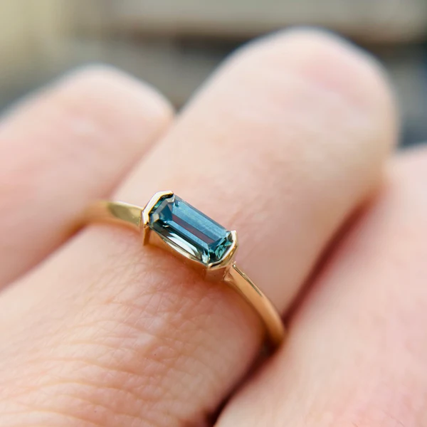 10k yellow gold green step cut sapphire minimalist engagement ring.  Worn on hand.