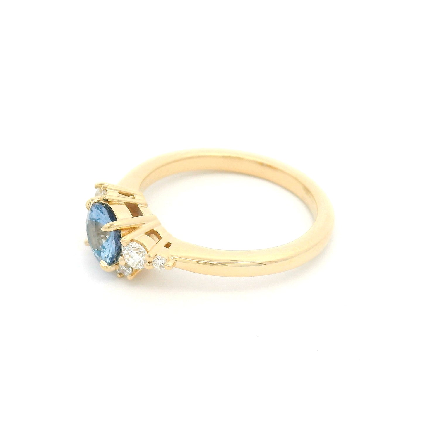 14K yellow gold engagement ring with a natural 0.82ct unheated round Sri Lankan cornflower blue sapphire and asymmetrical scatter of eight natural diamonds.