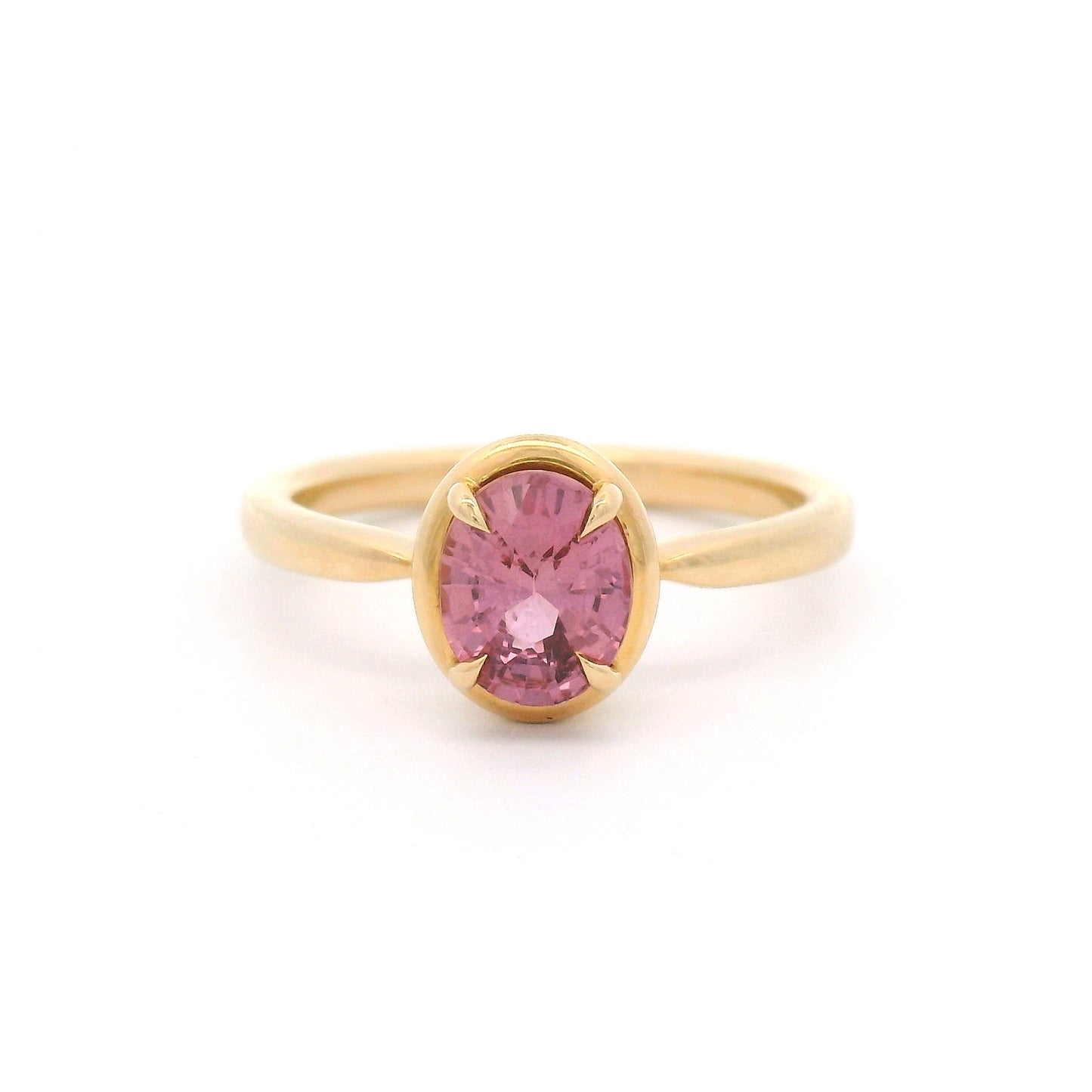 14K yellow gold solitaire engagement ring featuring a claw-set natural 1.20ct oval mixed-cut pink sapphire with a slim gold frame and a slender band tapering toward the setting.