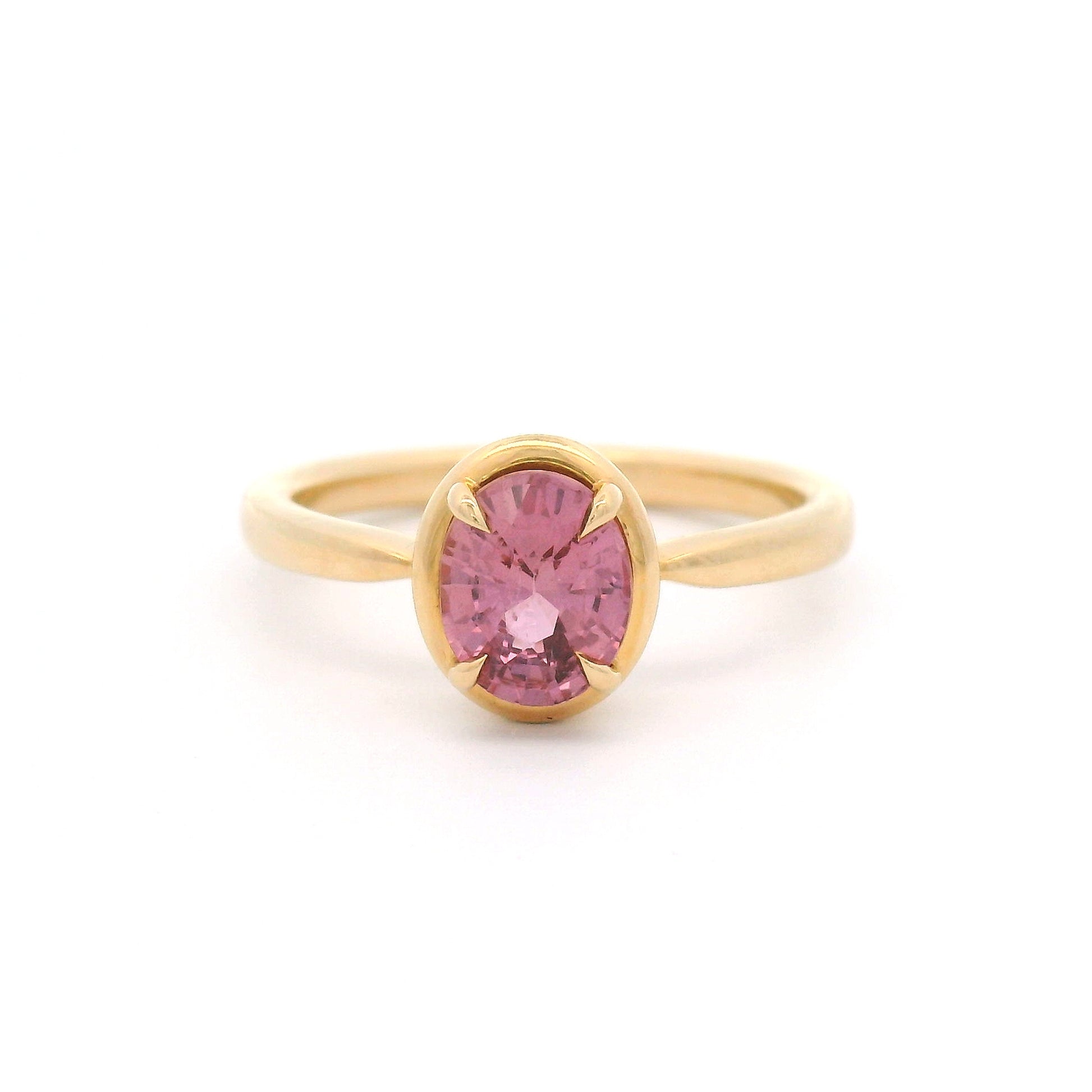 14K yellow gold solitaire engagement ring featuring a claw-set natural 1.20ct oval mixed-cut pink sapphire with a slim gold frame and a slender band tapering toward the setting.