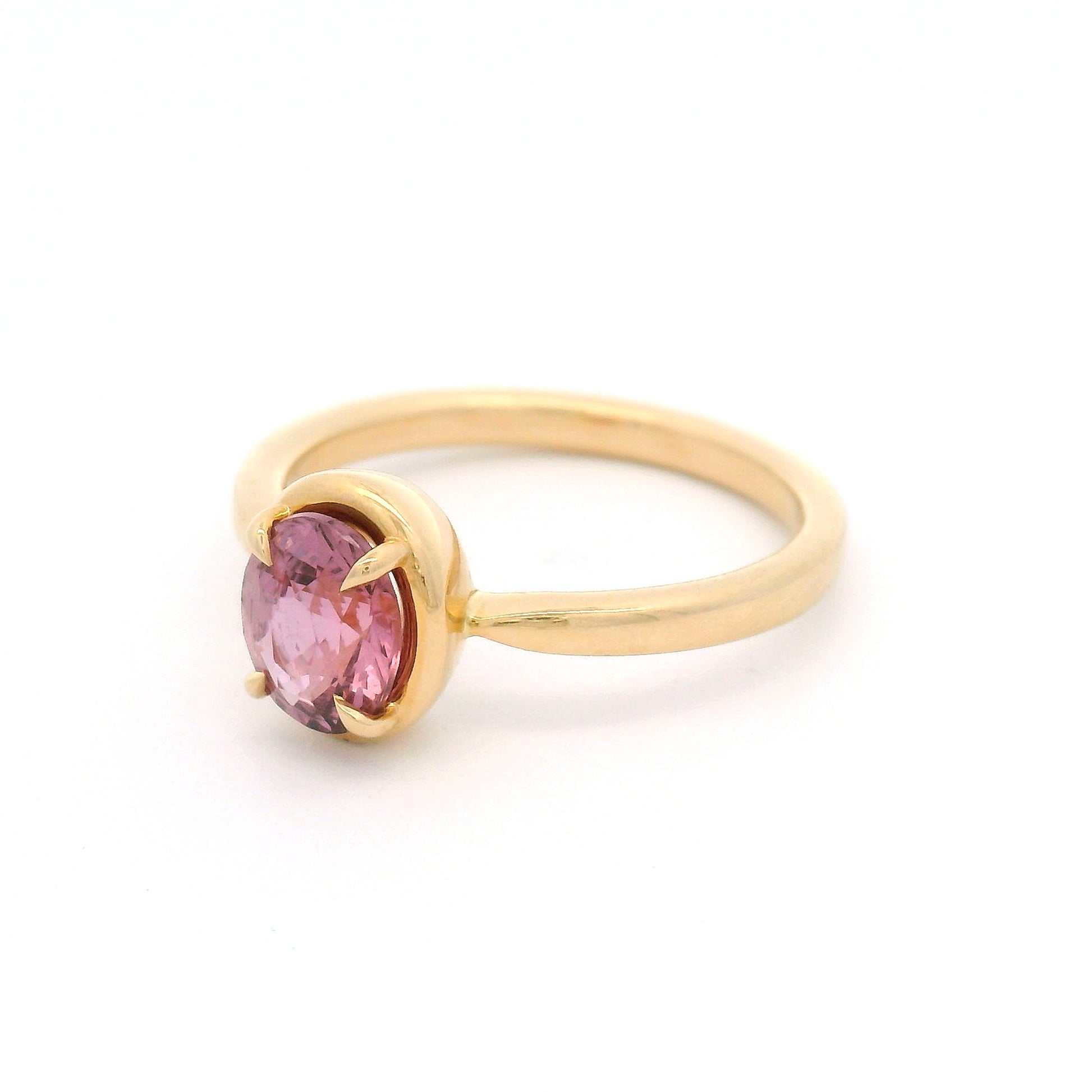 14K yellow gold solitaire engagement ring featuring a claw-set natural 1.20ct oval mixed-cut pink sapphire with a slim gold frame and a slender band tapering toward the setting.