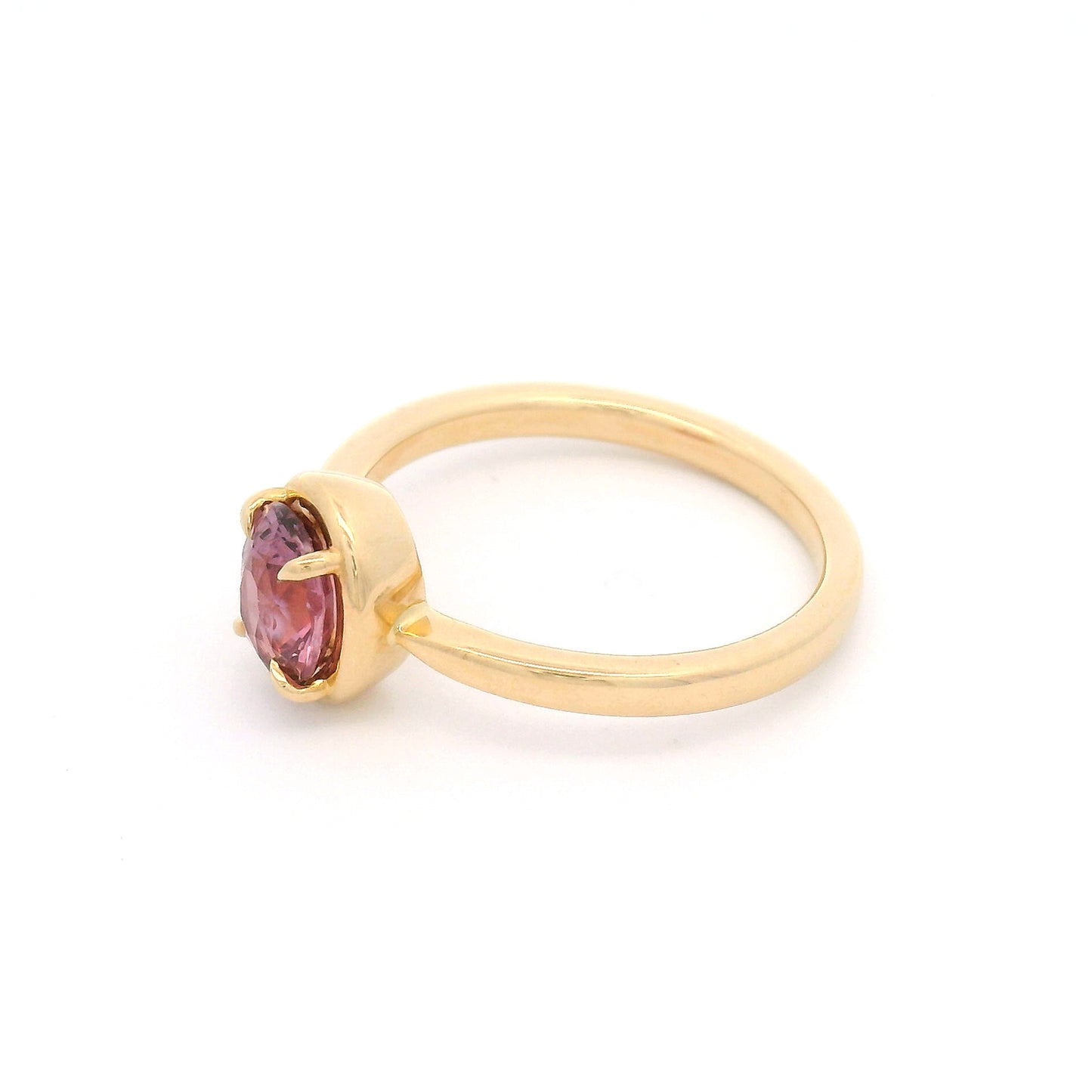 14K yellow gold solitaire engagement ring featuring a claw-set natural 1.20ct oval mixed-cut pink sapphire with a slim gold frame and a slender band tapering toward the setting.