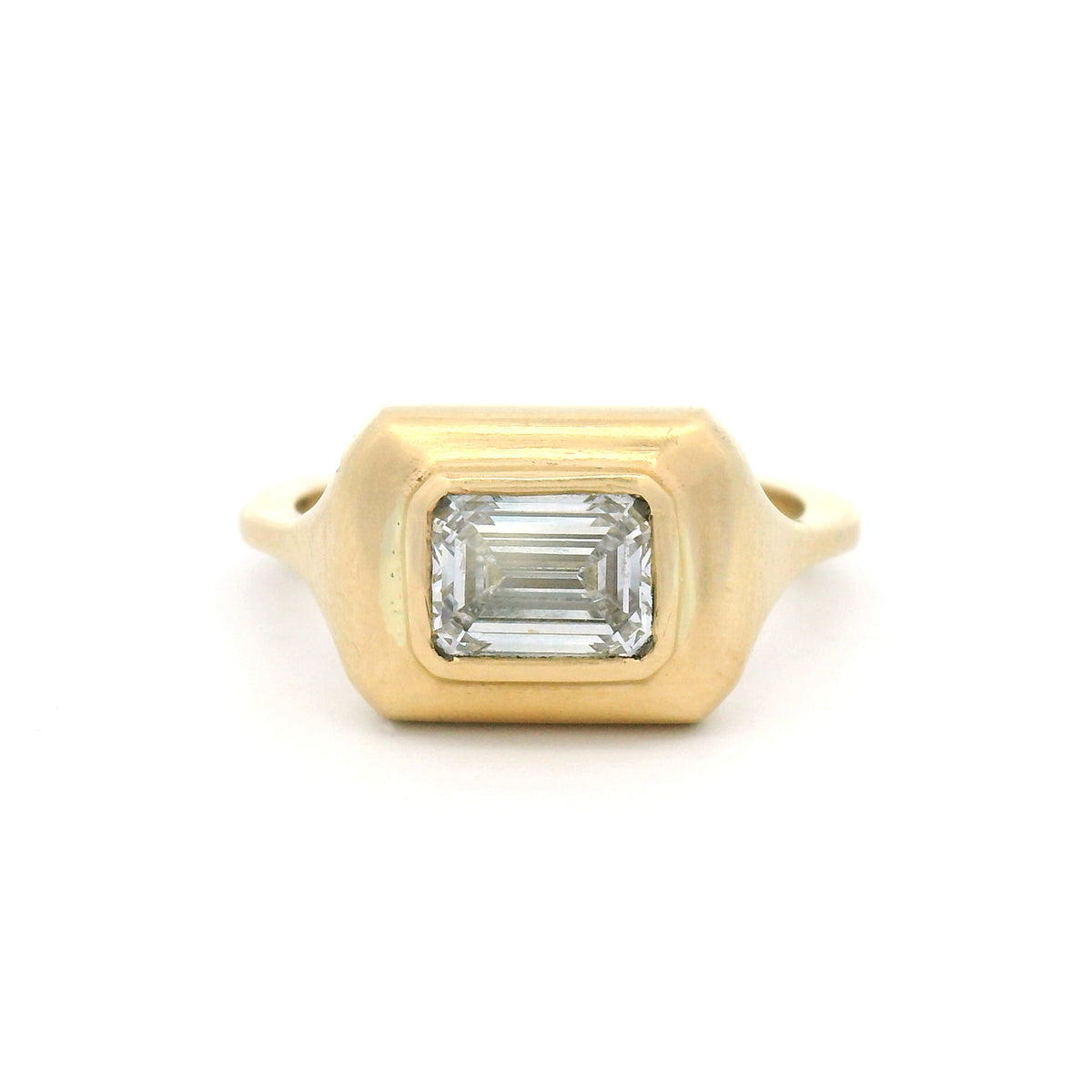 10K yellow gold bezel-set solitaire engagement ring with a 1.02ct lab-grown emerald-cut diamond, VVS2 clarity, D colour and satin-finished sculpted setting.