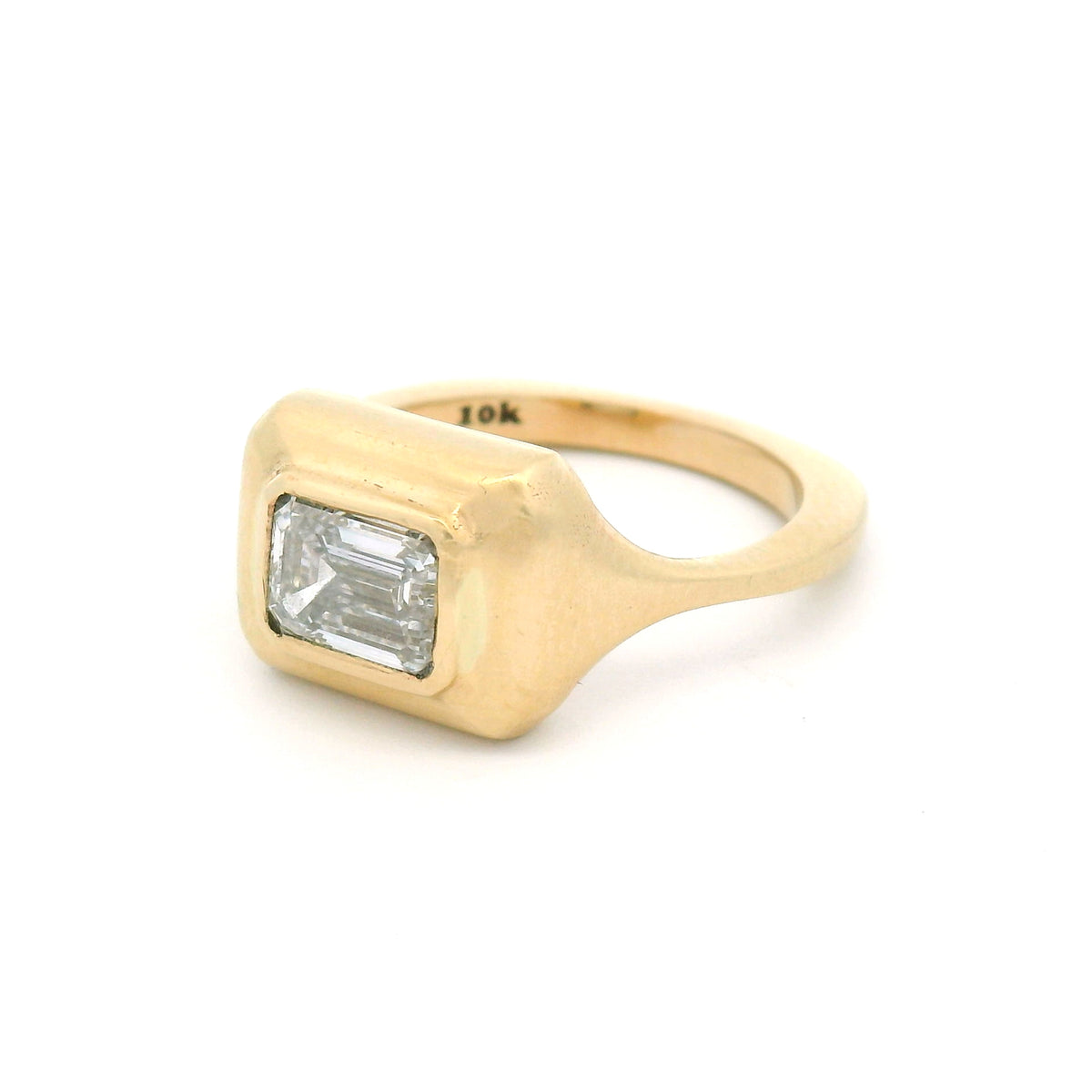 10K yellow gold bezel-set solitaire engagement ring with a 1.02ct lab-grown emerald-cut diamond, VVS2 clarity, D colour and satin-finished sculpted setting.