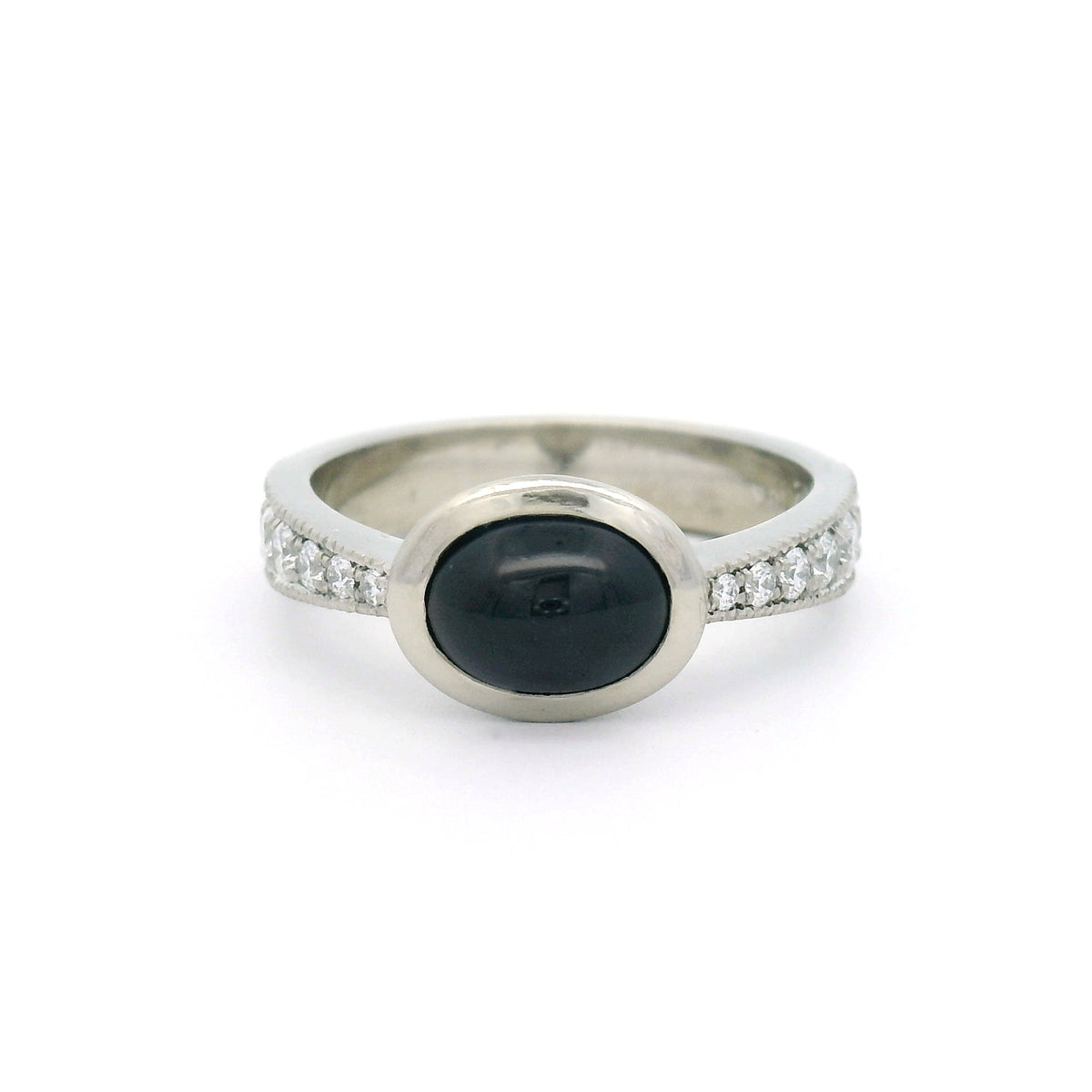 18K white gold bezel-set engagement ring with a natural 2.23ct oval cabochon blue sapphire and tapered band featuring 12 natural round brilliant-cut diamonds.