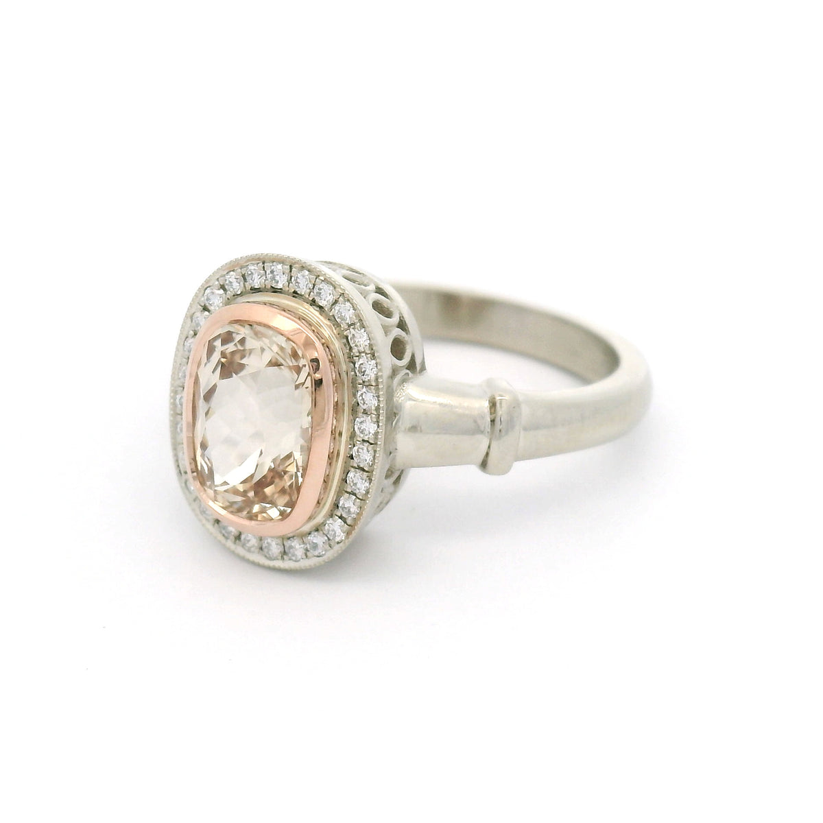 18K white gold engagement ring with a 14K rose gold bezel, natural 1.95ct cushion-cut peach sapphire, 28 natural diamonds and wire undergallery details.