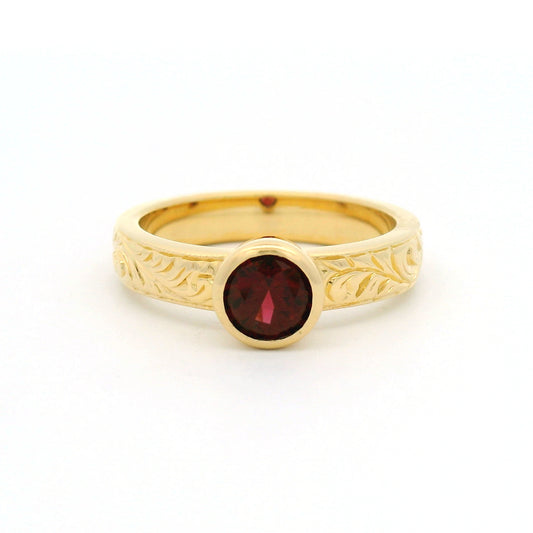 18K yellow gold bezel-set solitaire ring with a natural 0.68ct round red spinel and nature-inspired hand engraving on the 3.8mm band.