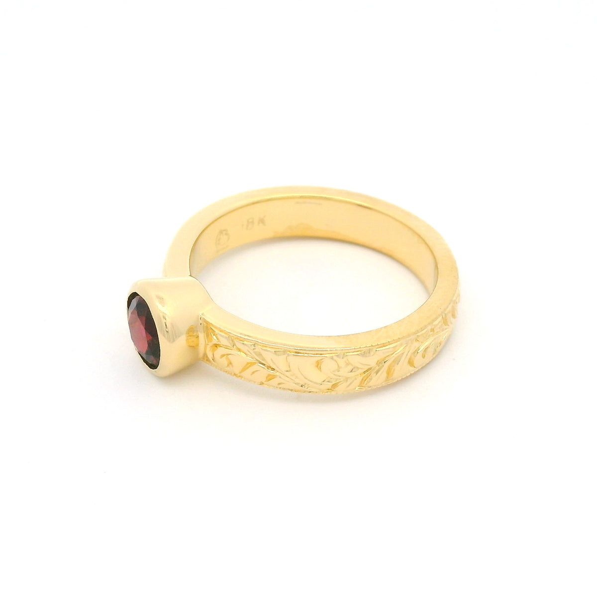 18K yellow gold bezel-set solitaire ring with a natural 0.68ct round red spinel and nature-inspired hand engraving on the 3.8mm band.