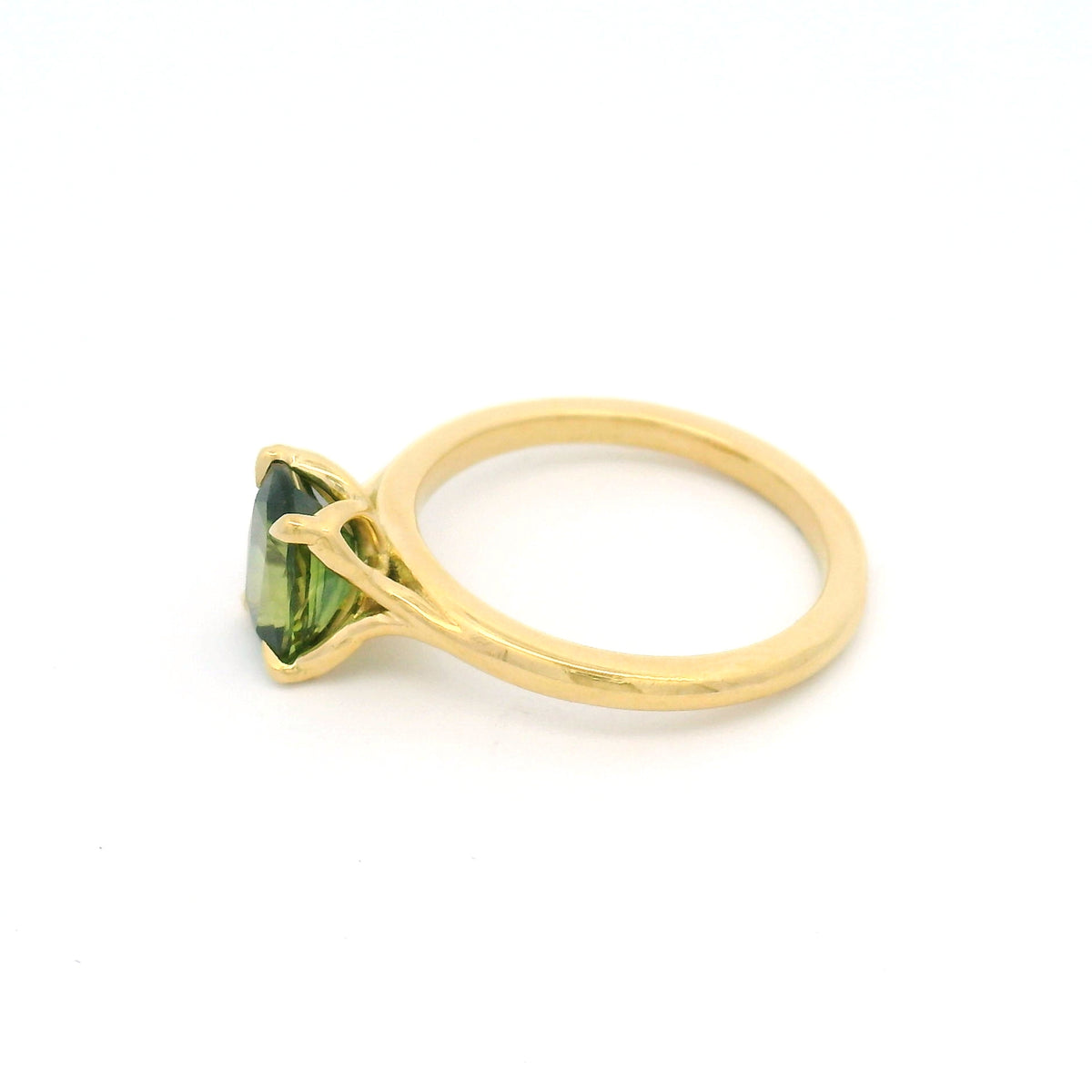 18K yellow gold four-claw solitaire engagement ring with a natural 1.54ct cushion-cut green sapphire, 1.8mm band and fine wire leaf details beneath the stone.
