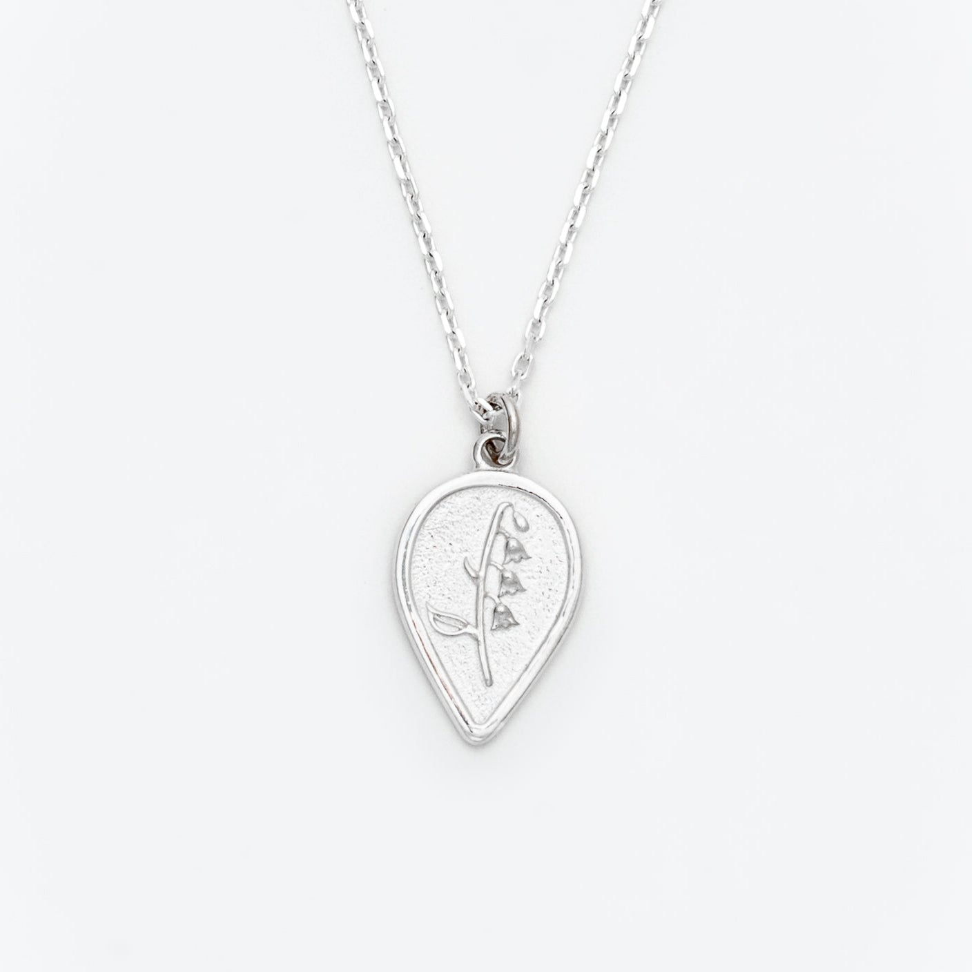 Silver necklace with a teardrop-shaped pendant on a white background