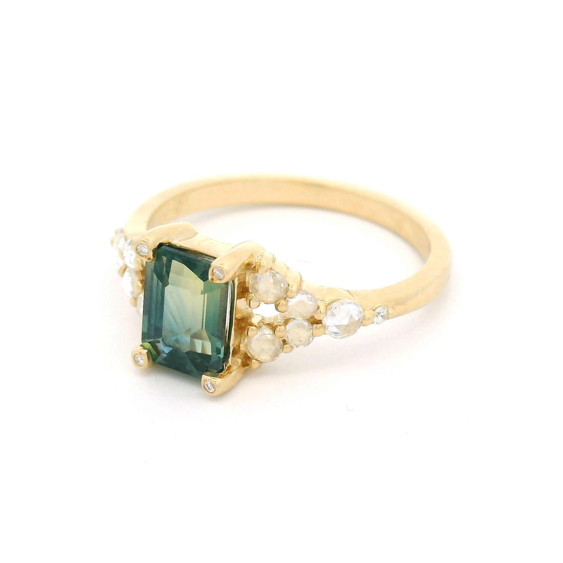14K yellow gold split shank engagement ring featuring a 1.25ct emerald-cut bluish-green bi-colour sapphire with rose-cut and round brilliant-cut diamond accents.