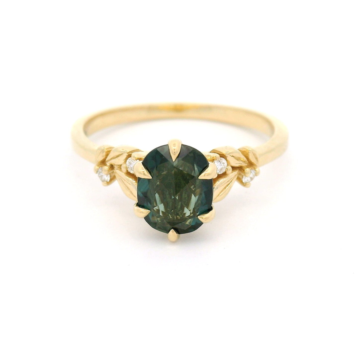 14K yellow gold engagement ring featuring a 1.1ct oval rose-cut green sapphire with diamond accents and sculpted leaf detailing on a delicate band.