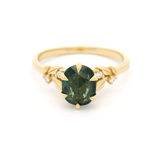 14K yellow gold engagement ring featuring a 1.1ct oval rose-cut green sapphire with diamond accents and sculpted leaf detailing on a delicate band.
