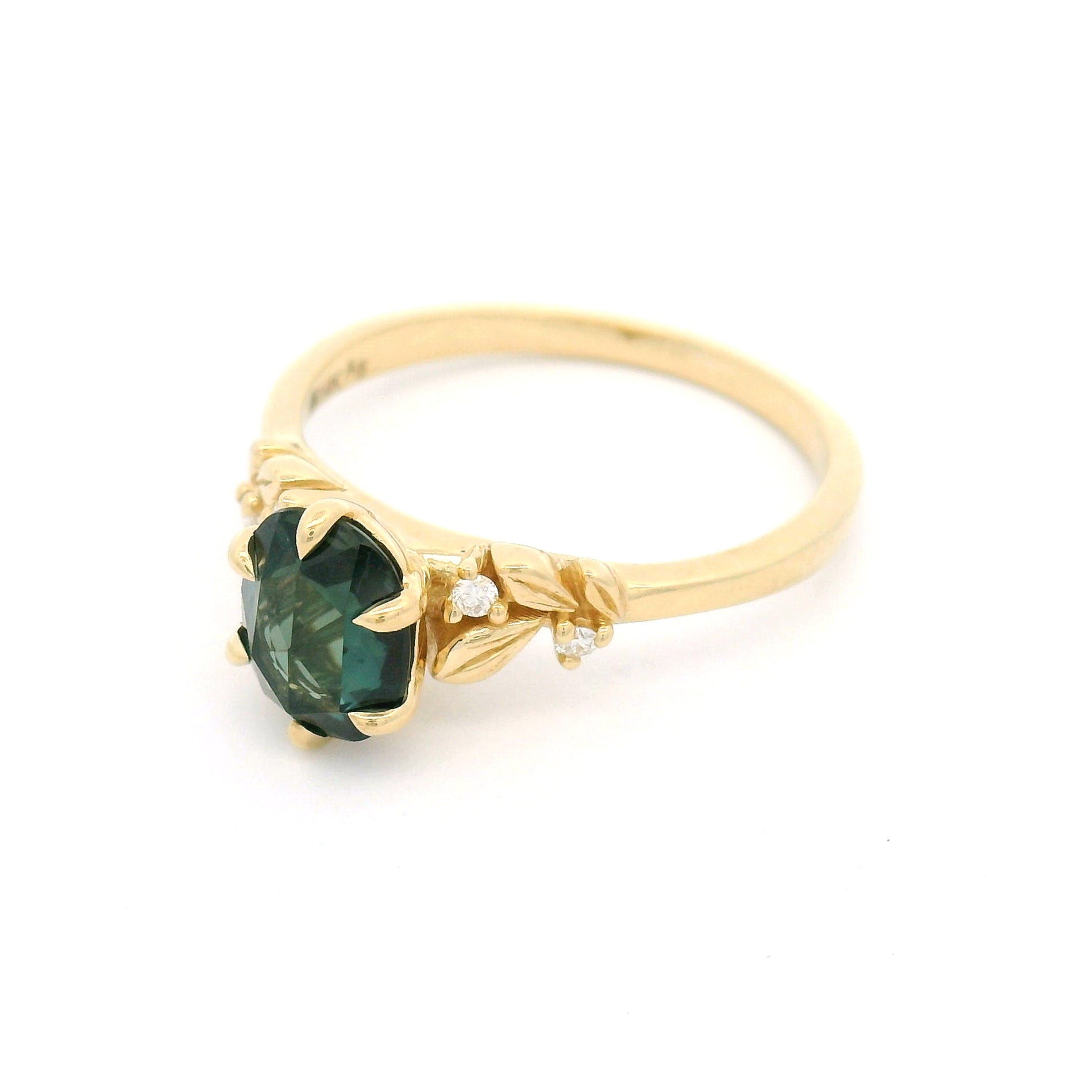 14K yellow gold engagement ring featuring a 1.1ct oval rose-cut green sapphire with diamond accents and sculpted leaf detailing on a delicate band.