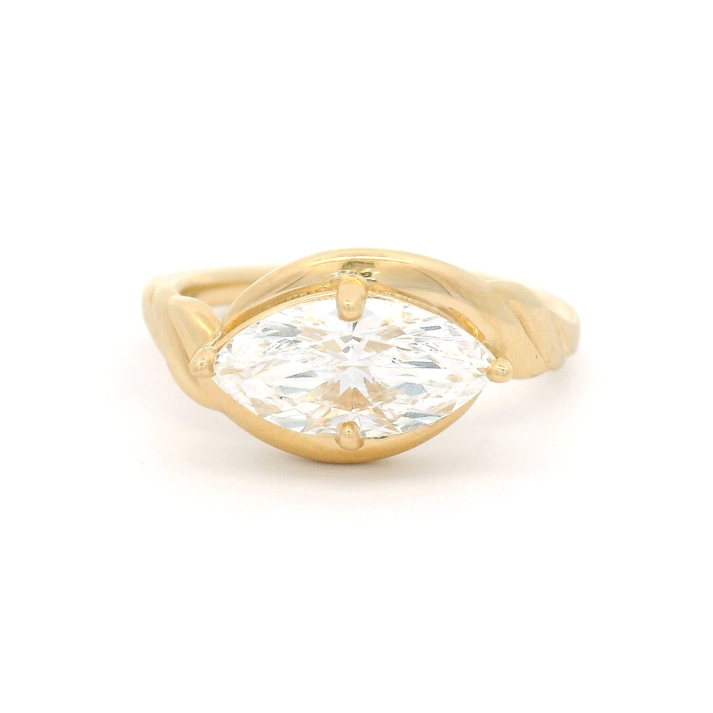 14K yellow gold low-profile solitaire engagement ring featuring a claw-set 1.40ct marquise-cut lab-grown diamond with VVS2 clarity, D colour, and ribbon-like setting details.