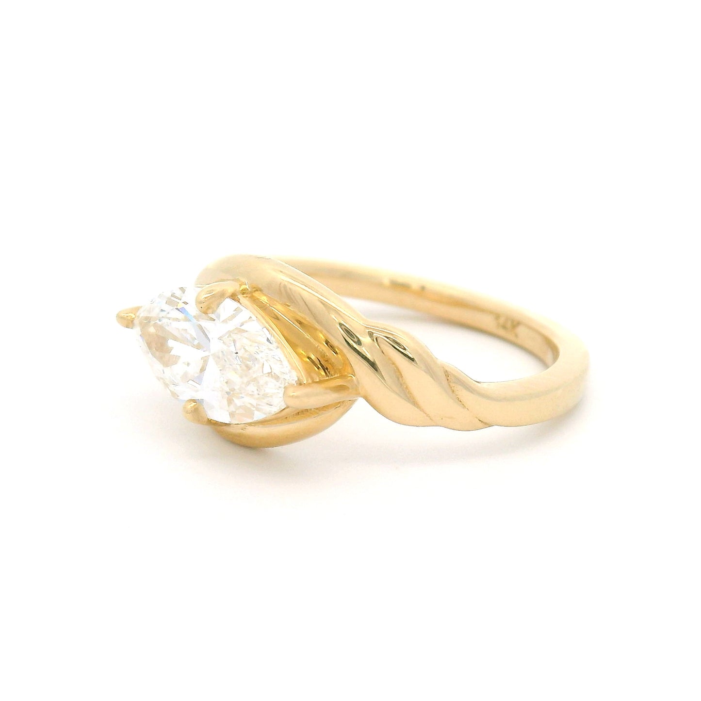 14K yellow gold low-profile solitaire engagement ring featuring a claw-set 1.40ct marquise-cut lab-grown diamond with VVS2 clarity, D colour, and ribbon-like setting details.