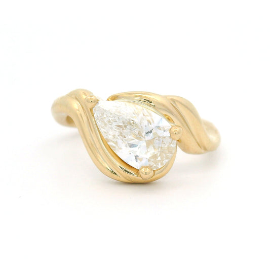 14K yellow gold low-profile solitaire engagement ring with a claw-set 1.25ct pear-shaped lab-grown diamond and sculptural ribbon-like setting.