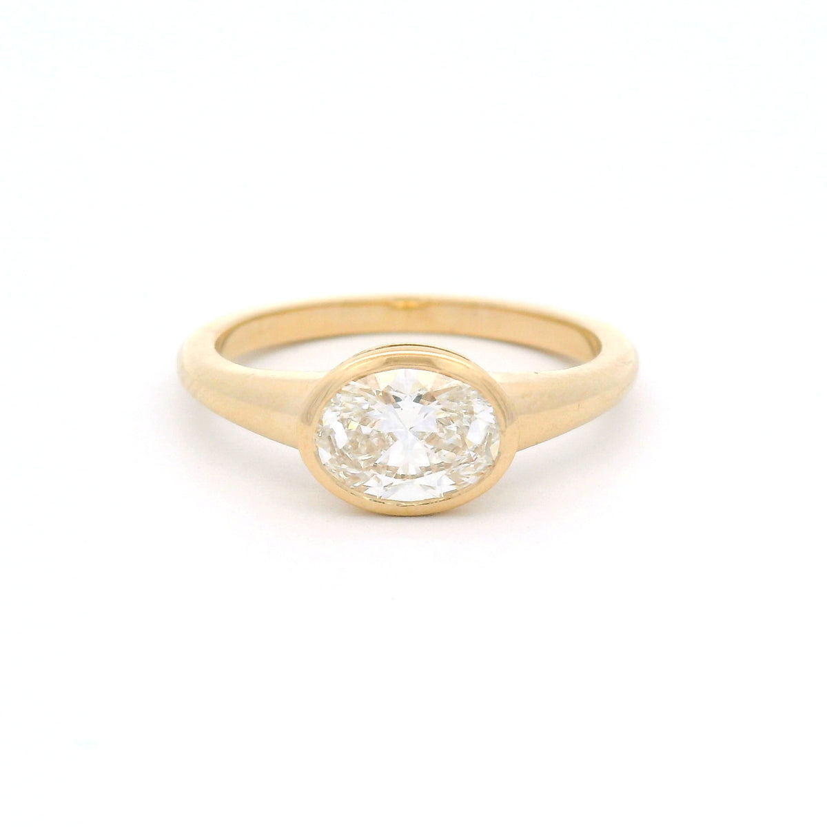 14K yellow gold east-west oval bezel solitaire ring with a 1.0ct lab-grown diamond, tapering shoulders and low-profile signet-inspired design.