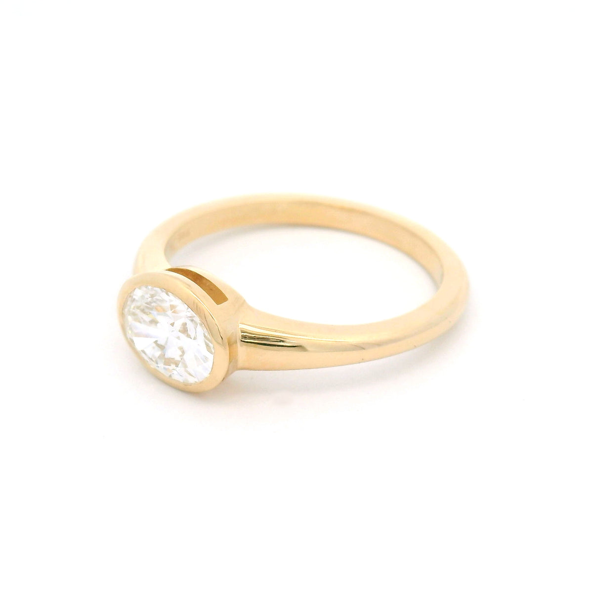 14K yellow gold east-west oval bezel solitaire ring with a 1.0ct lab-grown diamond, tapering shoulders and low-profile signet-inspired design.
